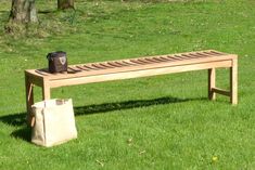 a wooden bench sitting on top of a green grass covered field next to a bag