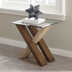 a glass and wood table with an origami star decoration on top, in front of a window