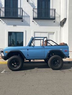 a blue pick up truck parked in front of a white building with balconies