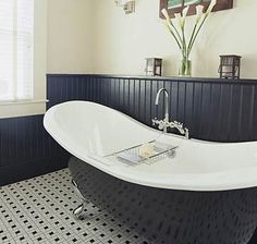 a bathroom with a black and white bathtub next to a window in the corner