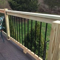 a wooden deck with metal railing and chairs