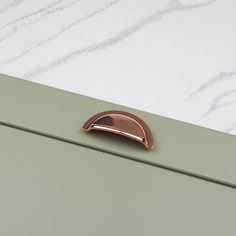 a close up of a door handle on a green cabinet with white marble in the background