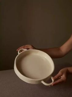 a person holding a white bowl on top of a table