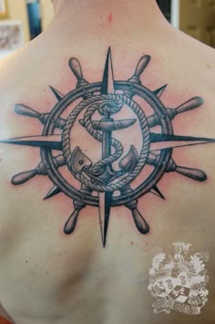 a man's back with an anchor and compass tattoo on it