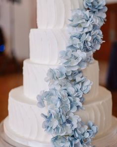 a white wedding cake with blue flowers on top