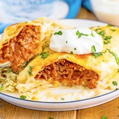 an enchilada on a plate with sour cream