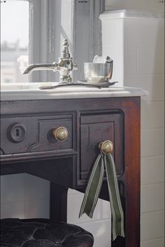 a bathroom sink sitting under a mirror next to a wooden vanity with a bow tie on it