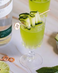 two glasses filled with green liquid and cucumber garnish