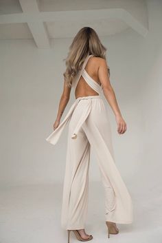 a woman is standing in front of a white background wearing a halter top and wide legged pants