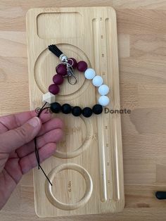 a person is making a beaded necklace with beads and scissors on a wooden board