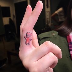 a person with a small tattoo on their finger making the peace sign and holding up her hand