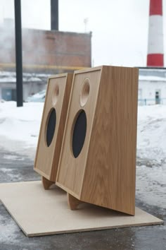 two wooden speakers sitting on top of a piece of wood in the middle of snow