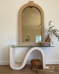 a mirror sitting on top of a table next to a vase and potted plant