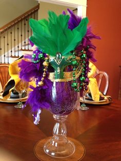 a vase with purple and green feathers on a table