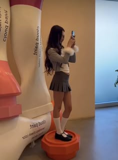 a woman taking a selfie with her cell phone in front of an art sculpture