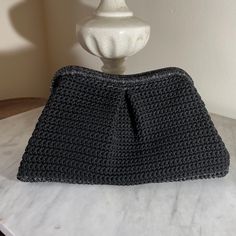 a black crocheted purse sitting on top of a white marble table next to a lamp