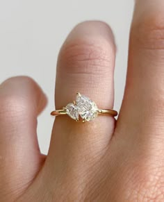 a woman's hand with a diamond ring on top of her finger, showing the side view