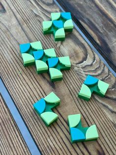 several pieces of green and blue paper sitting on top of a wooden table next to scissors