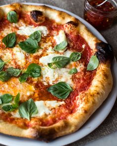 a pizza with basil leaves on it sitting on a plate