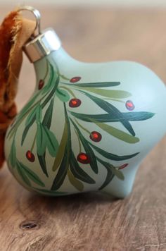 a small glass ornament with an olive tree design on the side and a piece of wood sticking out of it