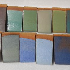 there are many different colors of soaps on the counter together in this row and one is blue, green, gray, and white