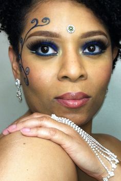 a close up of a woman with blue eyes and jewelry on her head, wearing an elaborate tiara