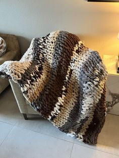 a couch with a blanket on top of it in a living room next to a lamp