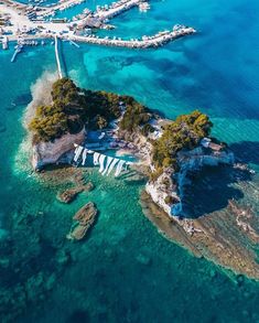 an island in the middle of blue water surrounded by land and boats on top of it