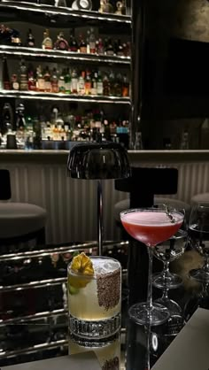 two cocktails sitting on top of a bar next to each other