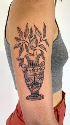 a woman's arm with a vase tattoo on the left side of her body