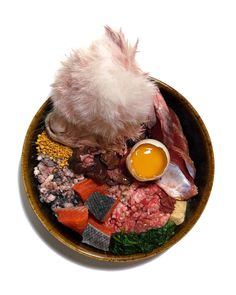 a bowl filled with meat and vegetables on top of a white table next to an egg