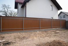 a house with a brown fence in front of it and a white building behind it