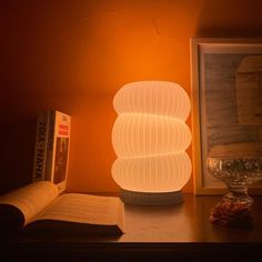 an illuminated lamp sitting on top of a table next to a book and glass bowl