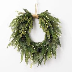 a christmas wreath hanging on the wall with berries and greenery around it's edges