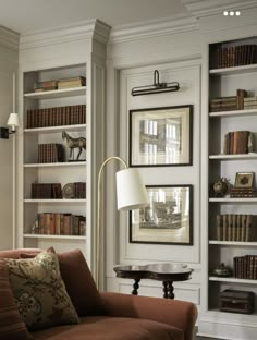 a living room filled with furniture and bookshelves next to a lamp on a table