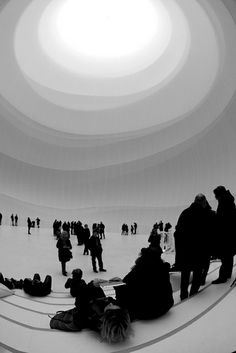 black and white photograph of people sitting on the floor in a circular room with skylight