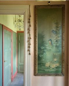 an ornate painting hangs on the wall next to a doorway with a chandelier