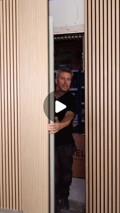 a man standing in front of a wooden wall with vertical slats on the walls