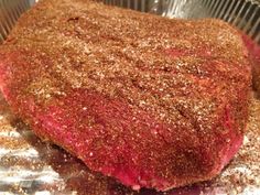 a large piece of meat sitting on top of a metal pan covered in seasoning