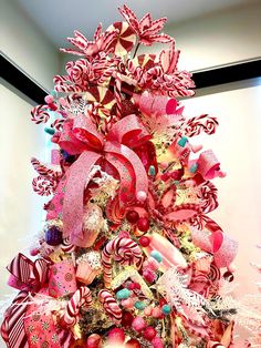 a pink christmas tree decorated with candy canes, candies and other holiday decorations