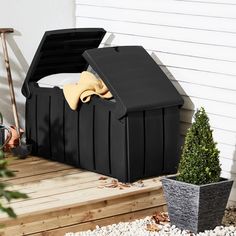 a black storage box sitting on top of a wooden deck next to a potted plant