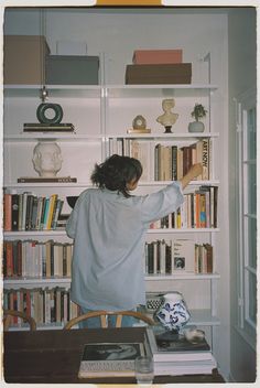 a woman standing in front of a book shelf filled with books