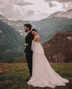 a bride and groom standing on top of a mountain