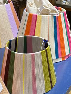 colorful lampshades are sitting on a table in front of some other items that have been made out of yarn