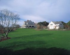 two large white houses sitting on top of a lush green field