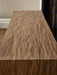 a wooden table top sitting in front of a window next to a wall with curtains