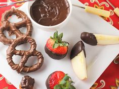 chocolate dipped strawberries, pretzels and apples on a plate with spoons