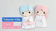 an origami paper doll with pink hair and blue eyes wearing a white dress