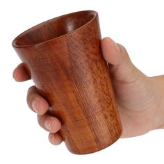 a hand holding a wooden cup in it's left hand on a white background