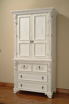 an antique white armoire with drawers and doors